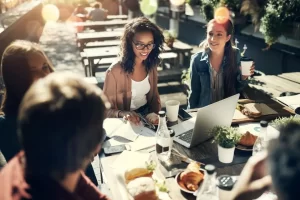 Different people working with laptops at a dinner table