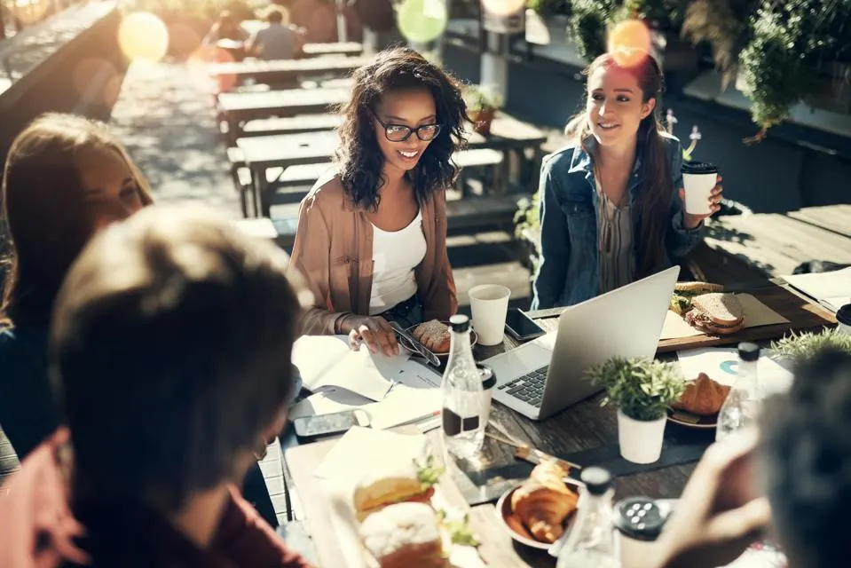 Different people working with laptops at a dinner table